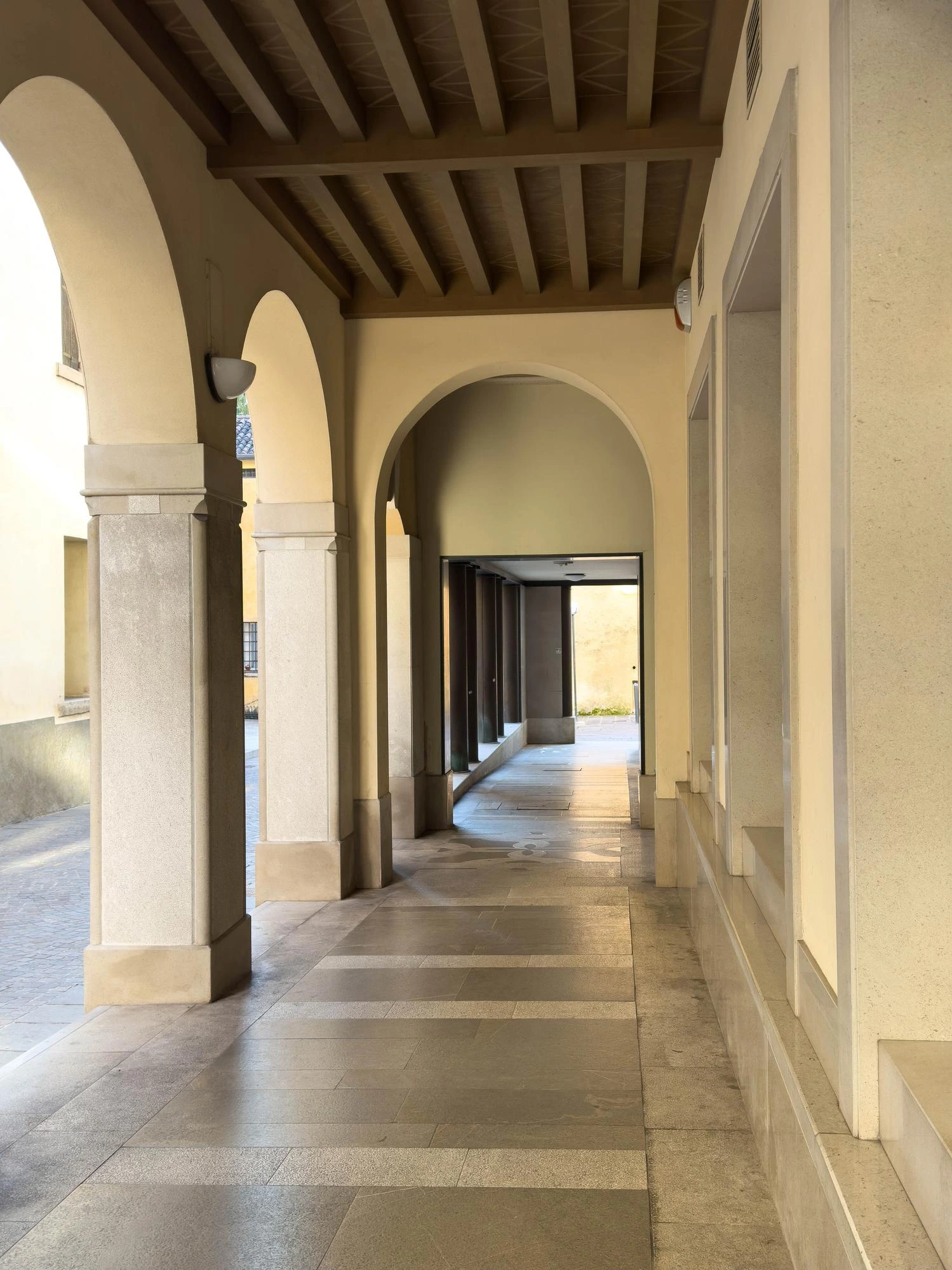 Quiet architectural corridor with arches and warm stone walls